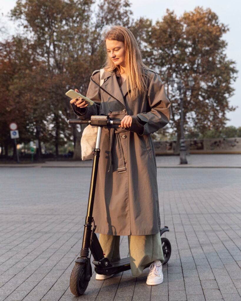 woman-checking-her-smartphone-while-electric-scooter-outdoors-1-819x1024.jpg
