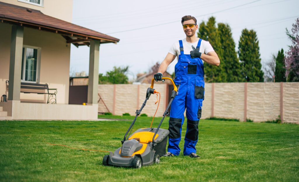 young-man-mows-lawn-using-electric-lawn-mower-special-worker-suit-near-large-country-house-backyard-1024x624.jpg