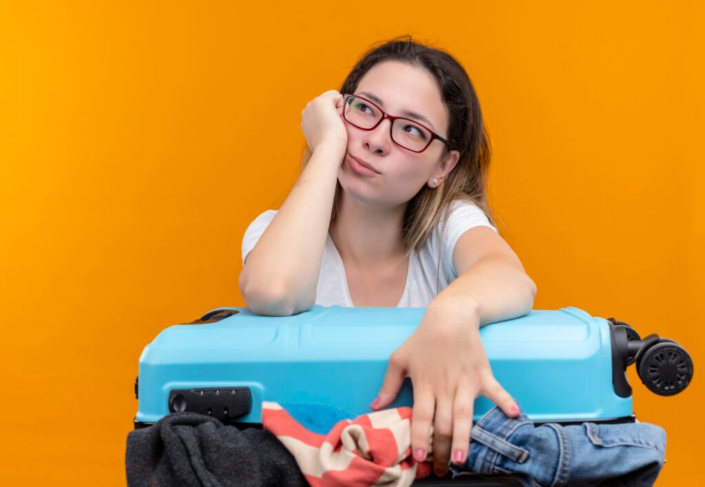 young-traveler-woman-white-t-shirt-holding-suitcase-full-clothes-leaning-head-hand-looking-aside-with-pensive-expressionon-face-standing-1024x707.jpg