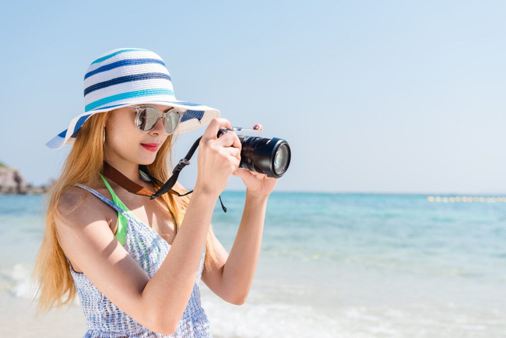 happy-asian-woman-vacation-photographing-with-camera-beach-with-horizon-background-1024x684.jpg