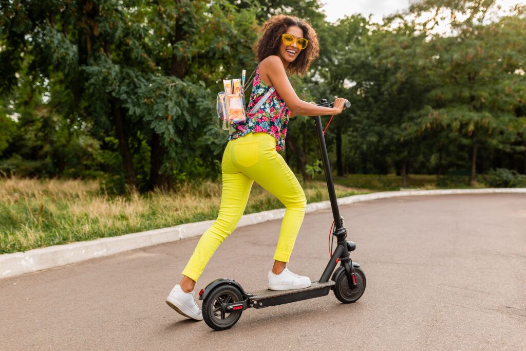 young-stylish-black-woman-having-fun-park-riding-electric-kick-scooter-summer-fashion-style-colorful-hipster-outfit-wearing-backpack-yellow-trousers-sunglasses-1024x683.jpg